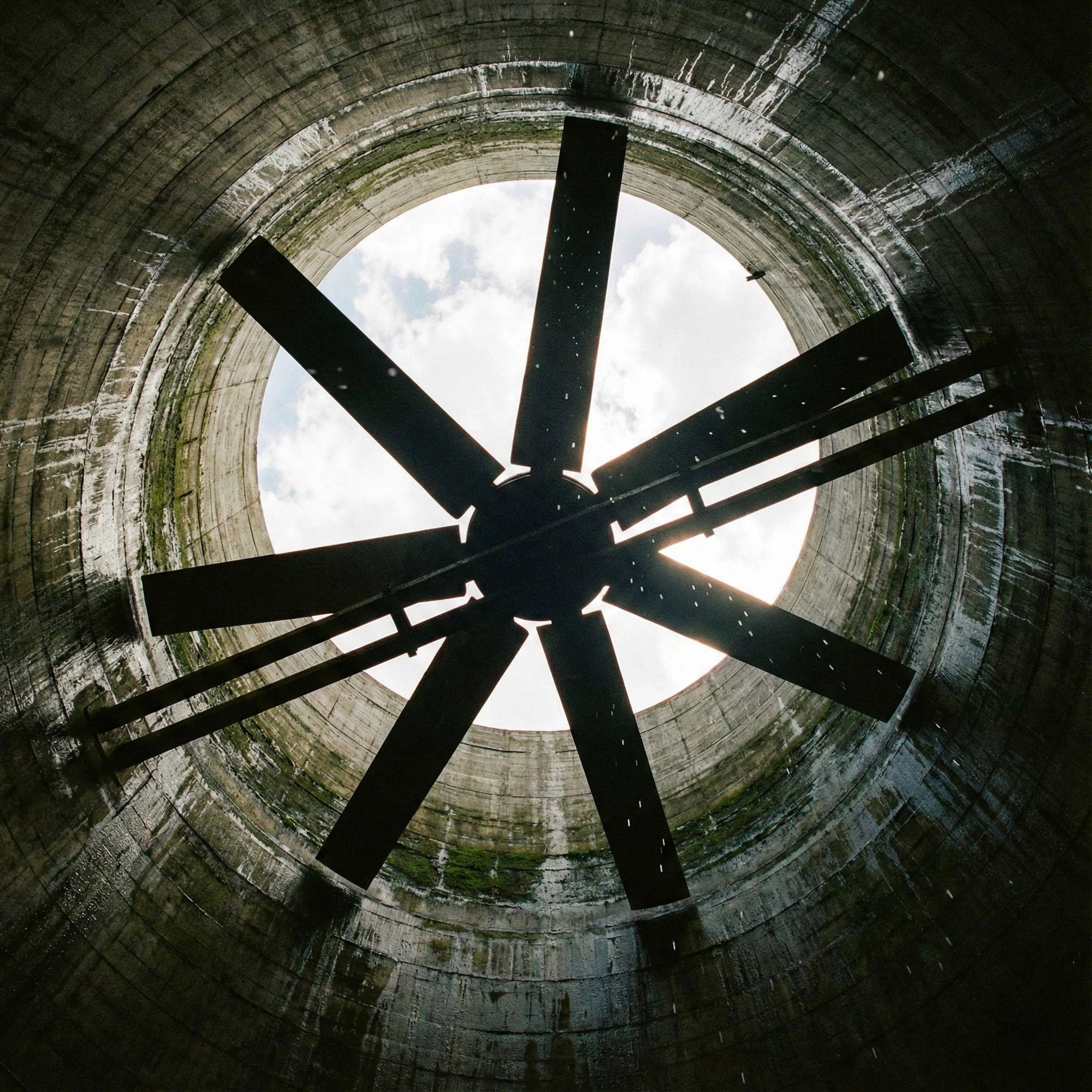 Looking up at the large rotating fan blades at the top of a cooling tower.